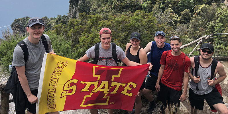 Students studying abroad in Italy hold up an Iowa State University flag