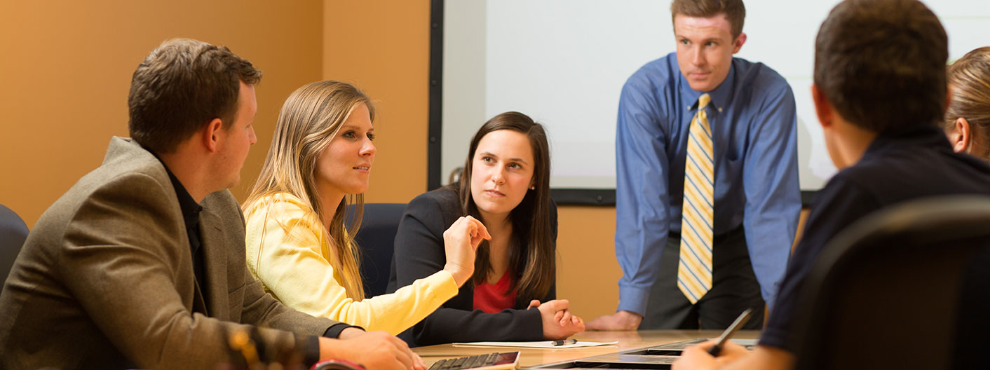 students interact around conference room table