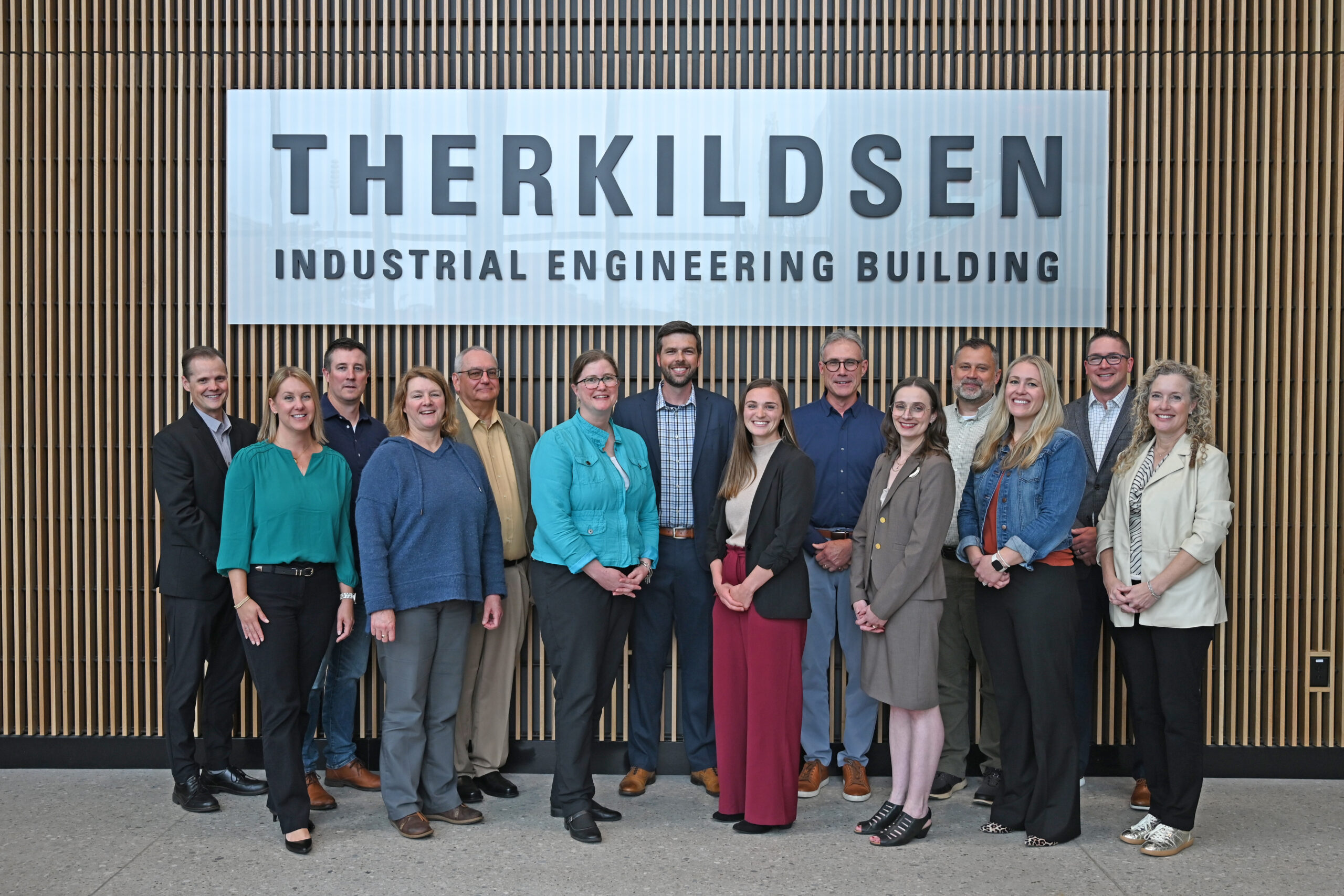 Group of advisory council members for the department in front of the Therkildsen Industrial Engineering Building sign.